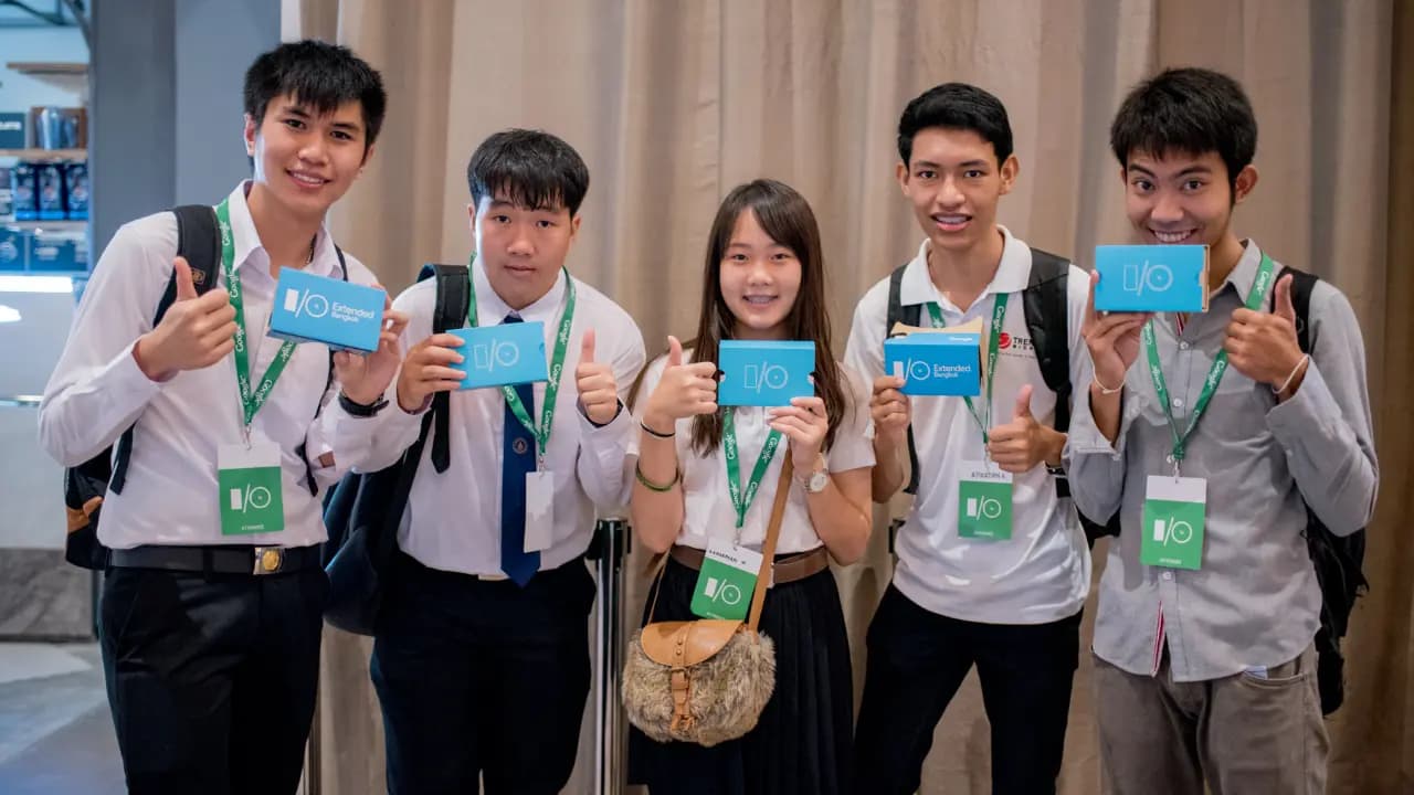 A group of young students proudly holding up a Google Cardboard labeled for the Google I/O event.